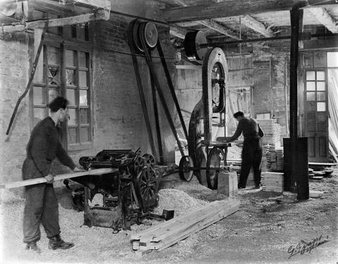 Due operai al lavoro: in primo piano si utilizza la macchina “pialla spessore”, in secondo piano la macchina "sega a bindello" (1940)