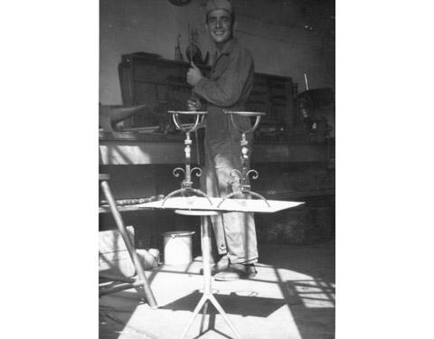Un giovane nella bottega scuola di Gino Piccolroaz: in primo piano due portafiori in ferro battuto (inizi del Novecento)