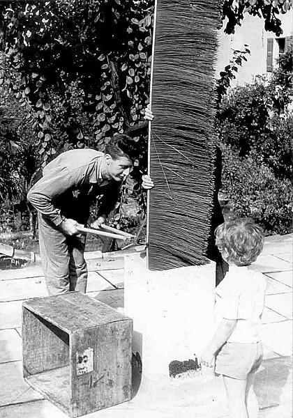 Il piccolo Andrea Acquaderni osserva due lavoratori mentre tagliano a misura la spazzola che esce sul tetto del garage, Bologna, 1958  