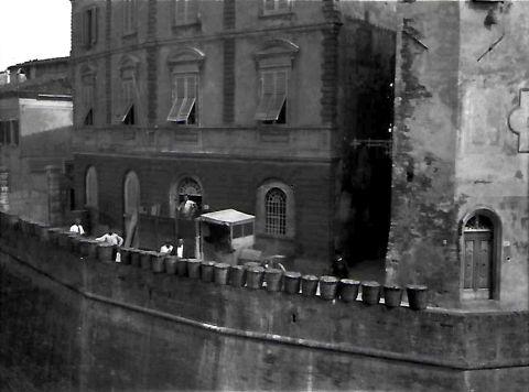 Le ceste con erbe aromatiche raccolte per la preparazione dei liquori (amari) messe ad essiccare sulle mura a Lari di fronte alla fabbrica di liquori in una foto d'epoca 