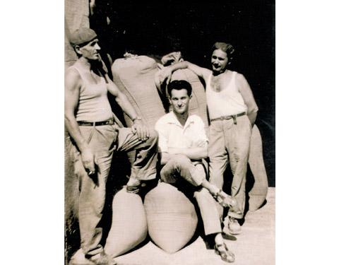 Tommaso Splendorini (il primo da destra) con due collaboratori davanti al magazzino di stoccaggio del grano in sacchi di juta (1950)